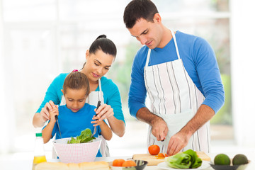 mother teaching little daughter mixing salad