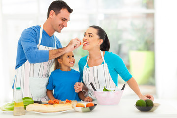 Obraz na płótnie Canvas loving husband feeding wife a piece of tomato while cooking