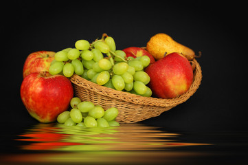 Basket with fruits above water on dark background