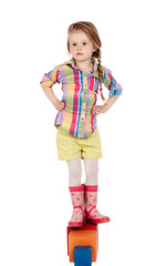 little girl sitting on the cube, isolated