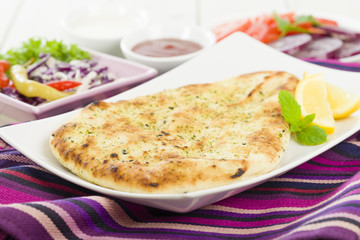 Garlic and coriander naan with lemon wedges and salad