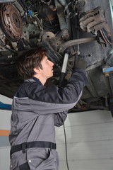 Fototapeta na wymiar Mechanic working under the car in the auto workshop
