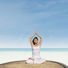 Fototapeta na wymiar Asian woman practicing yoga at beach