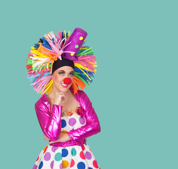 Pensive girl clown with a big colorful wig
