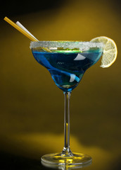 Blue cocktail in glass on color background