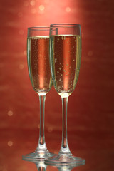 Two glasses of champagne on bright background with lights