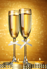 Two glasses of champagne on bright background with lights