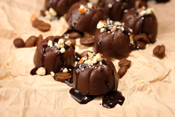 Chocolate candies and coffee beans, on beige paper background