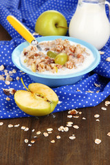 Useful oatmeal in bowl with fruit on wooden table close-up