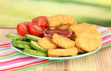 Fried chicken nuggets with vegetables and sauce on table in