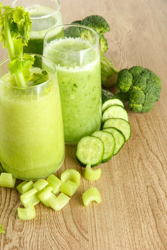 Glasses of green vegetable juice on wooden background