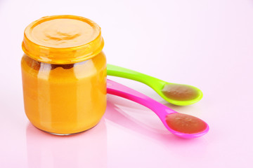 Baby food with weaning spoons on purple background