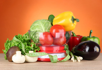 Fresh vegetables in scales on table on orange background