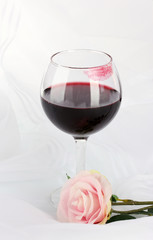 Glass of wine with lipstick imprint on white fabric background