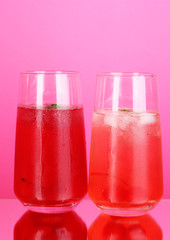 Two cherry cocktails with ice on pink background