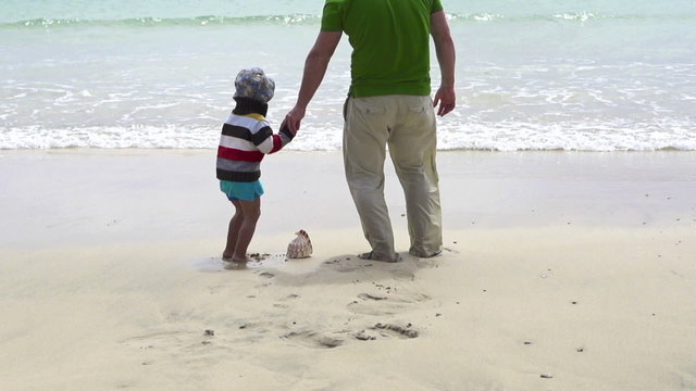 Father and son find beautiful seashell on the beach
