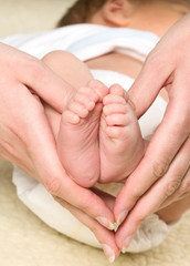 Mother is holding legs of baby boy