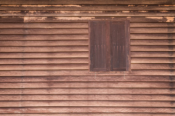 Wooden wall of ancient house with window closed