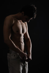 Fototapeta na wymiar Muscular Man looking his body isolated black background
