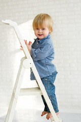 Smiling little boy standing on the step of a ladder