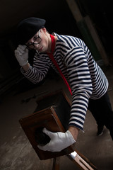 Portrait of a young handsome man in the image of a mime photographing an antique camera