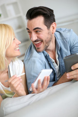 Cheerful couple having fun using smartphone