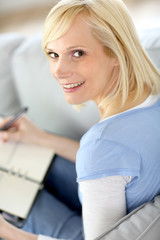 Young woman at home writing on agenda