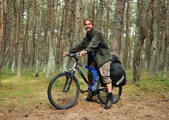 Young man on bicycle with backpack in forest - bicycle travel