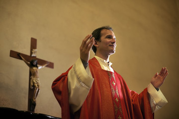 Catholic priest on altar praying during mass - obrazy, fototapety, plakaty
