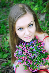 Naklejka premium Beautiful young woman with the bouquet of spring flowers