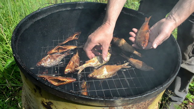 man hand take fresh smoked fish from smokehouse