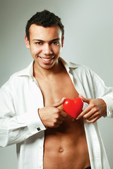 A young man holding a red heart on his hands