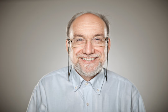 Portrait of old man taking glasses and smiling