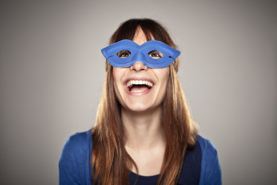 Portrait of a normal girl laughing with a blue mask