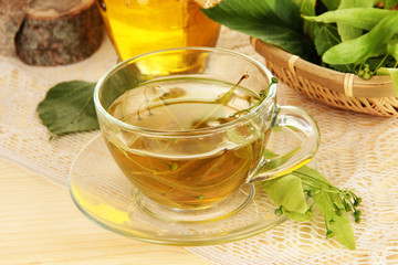 Glass cup of tea with linden on wooden table close-up