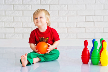 Baby boy playing with colorful plastic toy bowling