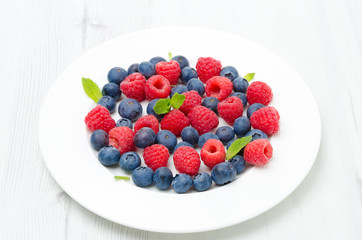 Fresh raspberries and blueberries on a white plate
