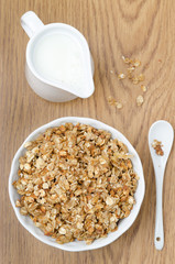 homemade muesli and jug of milk for breakfast on a wooden table