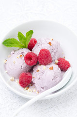 ice cream with fresh raspberries and mint in a bowl, vertical