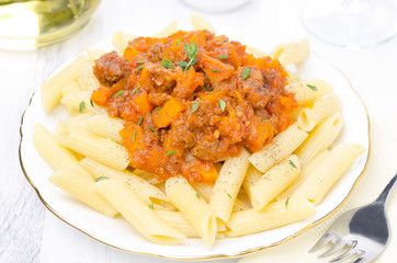 penne pasta with sauce of beef, tomato, pumpkin on a white plate