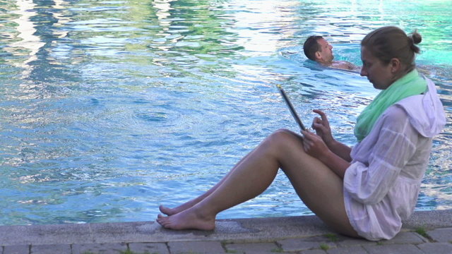 Woman with tablet sit by the pool, super slow motion