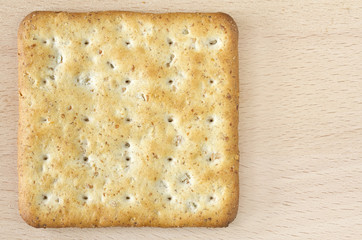 One wholegrain cracker on wooden board