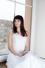 Beautiful bride sitting on the window sill