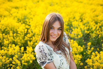 Naklejka na ściany i meble Beautiful woman among yellow flowers in a field