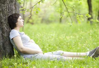 Naklejka na ściany i meble Pregnant woman relaxing in the park