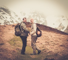 Happy young hiker couple with backpacks in mountains