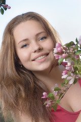 Fototapeta premium Portrait of the girl with a branch of a blossoming apple-tree