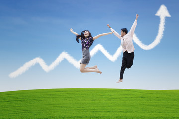 Fototapeta na wymiar Couple jumping on profit chart cloud