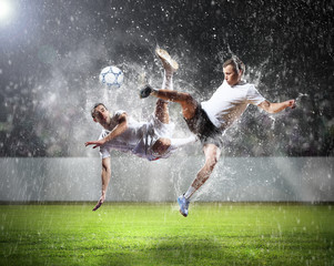 Obraz na płótnie Canvas two football players striking the ball