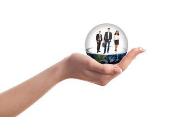 A woman's hand holding a glass ball with people inside